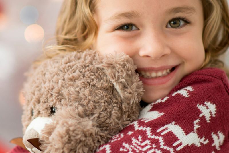 Little girl hugging a teddy bear.