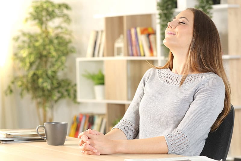 Woman in her home office taking a breath of fresh indoor air.